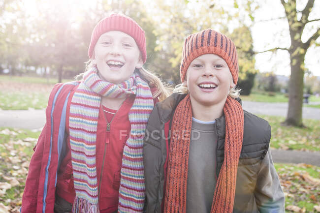 Portrait of brother and sister in park, smiling — Stock Photo
