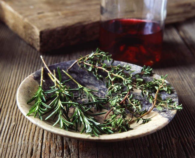 Rosemary and thyme in vintage bowl, glass of red wine — Stock Photo