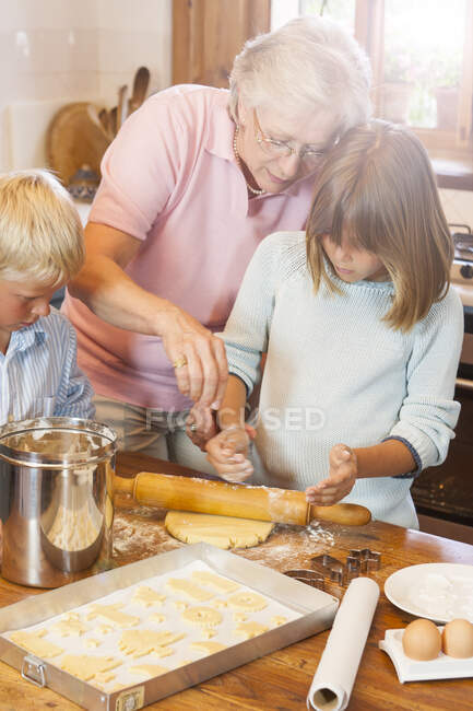 Abuela y nietos haciendo galletas - foto de stock