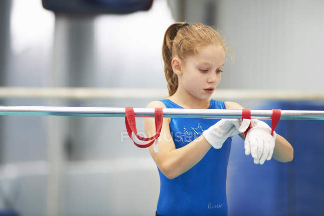 Young gymnast using training wrist straps to aid practise on bars — Stock Photo