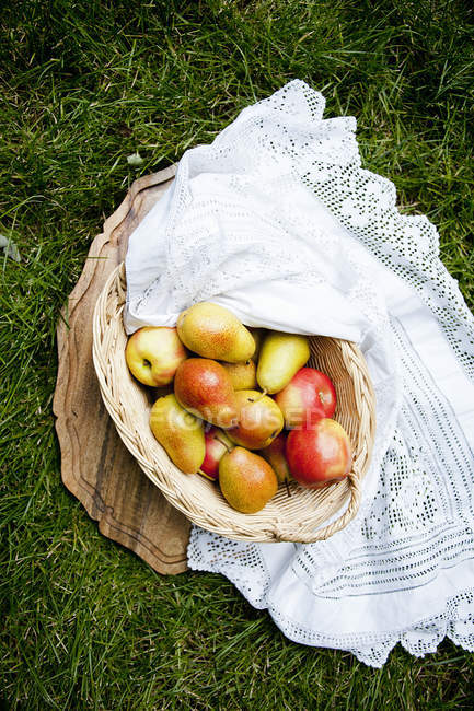 Cesta de maçãs e pêras na grama — Fotografia de Stock