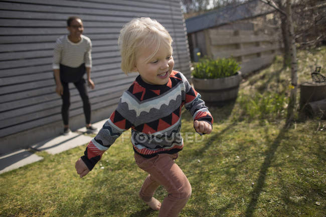 Boy running from mother in garden and smiling — Stock Photo