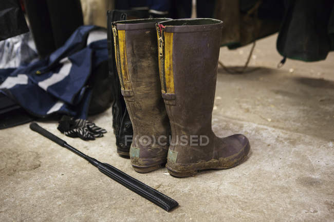 Horse riding boots and crop outdoors — Stock Photo