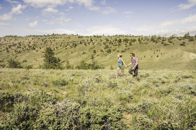 Adolescente e namorado correndo em colinas, Bridger, Montana, EUA — Fotografia de Stock