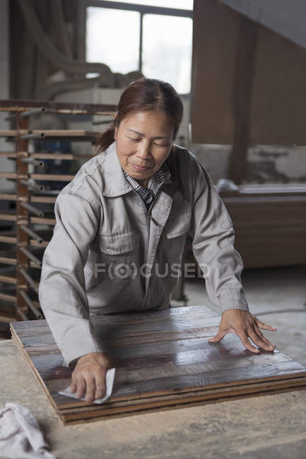 Carpenter smoothing surface of wooden plank with sandpaper in factory, Jiangsu, China — Stock Photo