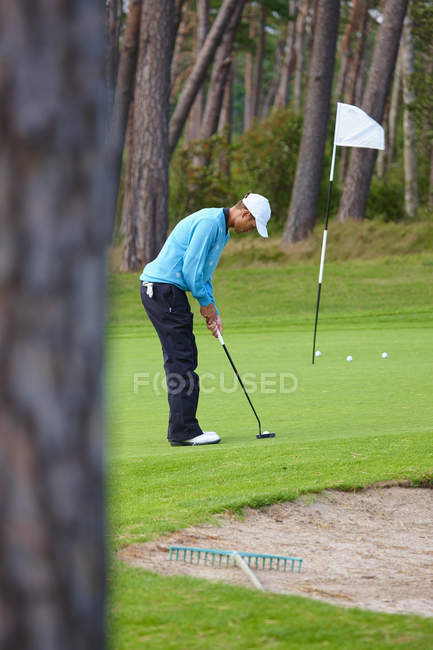 Vista lateral do golfista tomando um putt — Fotografia de Stock