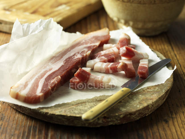 Pancetta with knife on vintage chopping board — Stock Photo