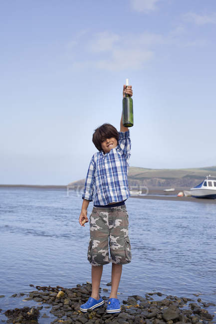 Menino segurando mensagem em garrafa à beira-mar — Fotografia de Stock