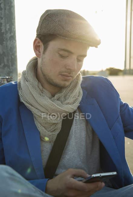 Young man leaning against wall texting on smartphone — Stock Photo