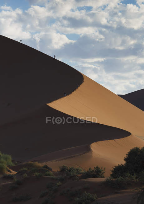 Silhouettes of two people hiking giant sand dune — Stock Photo