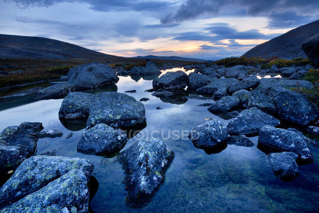 Aguas tranquilas y rocas en el río Chasnayok, montañas Khibiny, península de Kola, Rusia - foto de stock