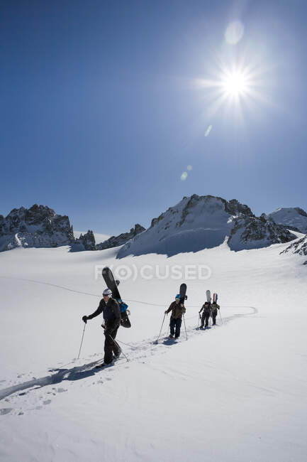Vier männliche Snowboarder wandern durch verschneite Landschaft, Trient, Schweizer Alpen, Schweiz — Stockfoto