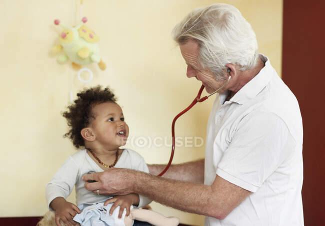 Pédiatre examinant une petite fille à l'aide d'un stéthoscope — Photo de stock