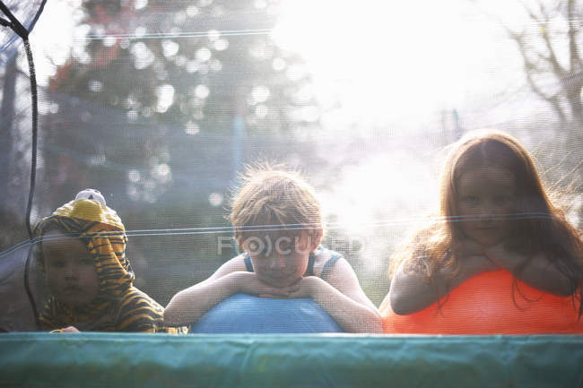Маленькие дети, выглядывающие из сада батут — стоковое фото