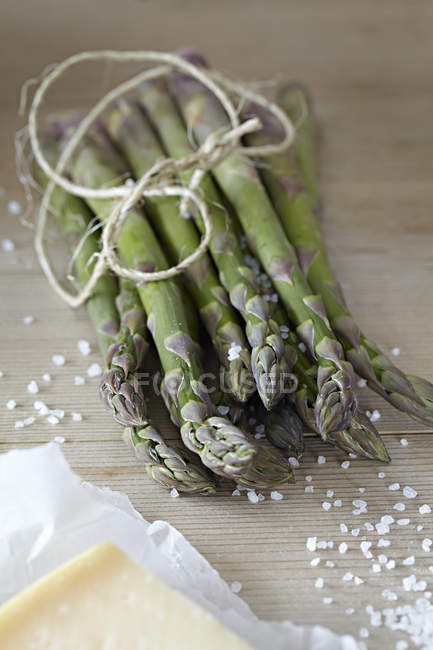 Un mazzo di asparagi in tavola con sale marino e formaggio — Foto stock