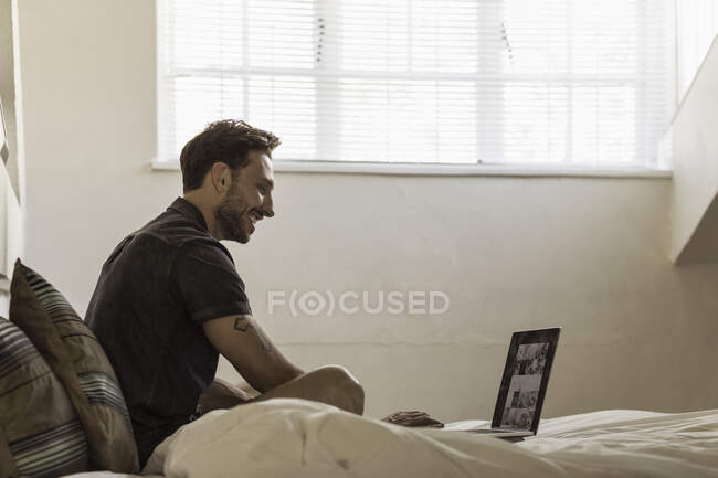 Homem na cama usando laptop — Fotografia de Stock