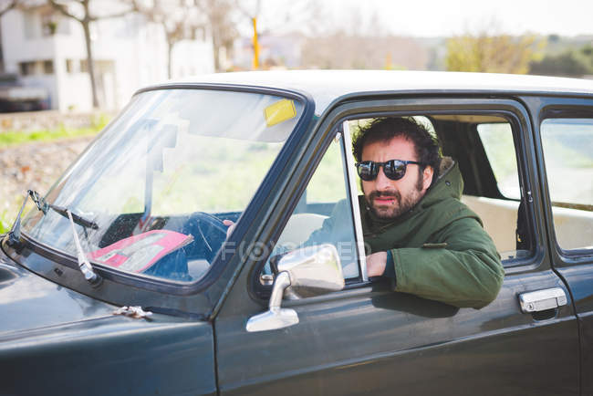 Портрет среднего взрослого мужчины за рулем винтажного автомобиля — стоковое фото