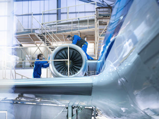Инженеры, работающие над авиационным двигателем на заводе по техническому обслуживанию — стоковое фото