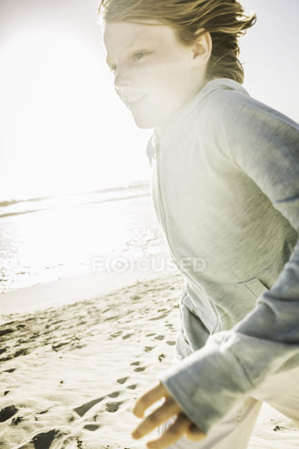 Garçon avec des cheveux soufflés par le vent sur la plage — Photo de stock