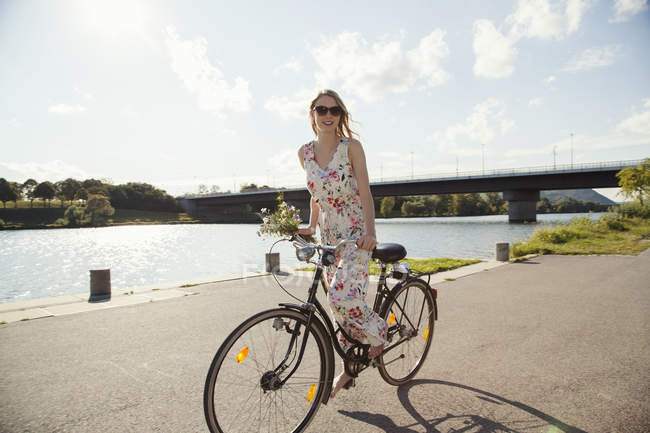 Молодая женщина на велосипеде вдоль берега реки, остров Дунай, Вена, Австрия — стоковое фото