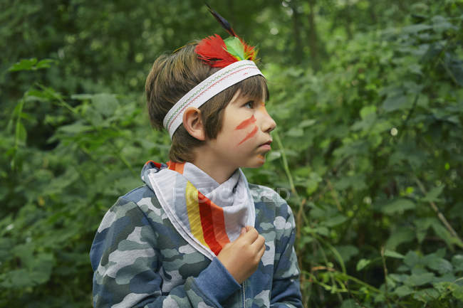 Boy dressed up in face paint playing in forest — Stock Photo