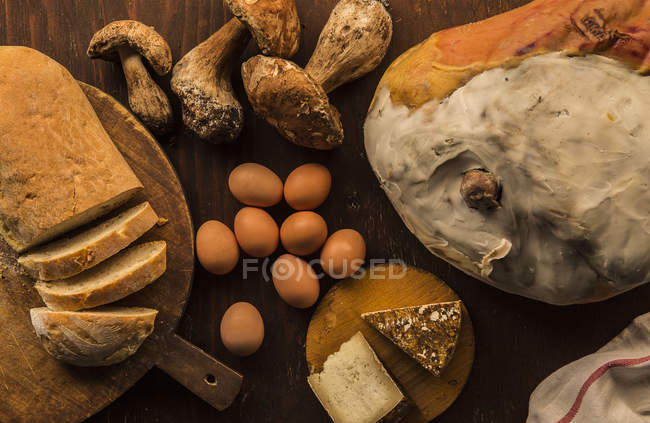 Vista superior del queso crudo y preparado, pan, huevos y champiñones porcini - foto de stock