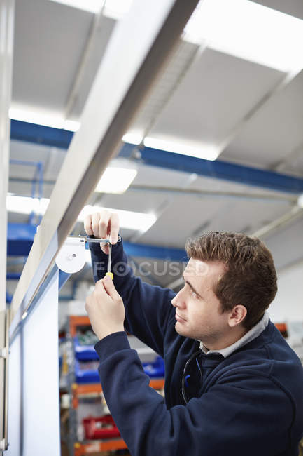 Male worker measuring roller blind in factory — Stock Photo
