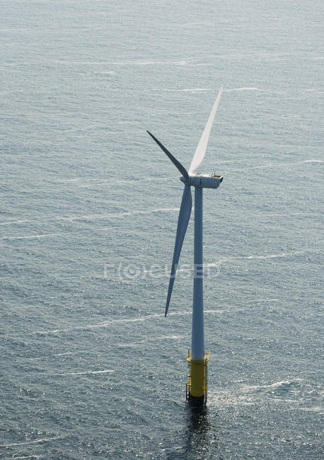 Vista aérea da turbina eólica sobre a água à luz do sol — Fotografia de Stock