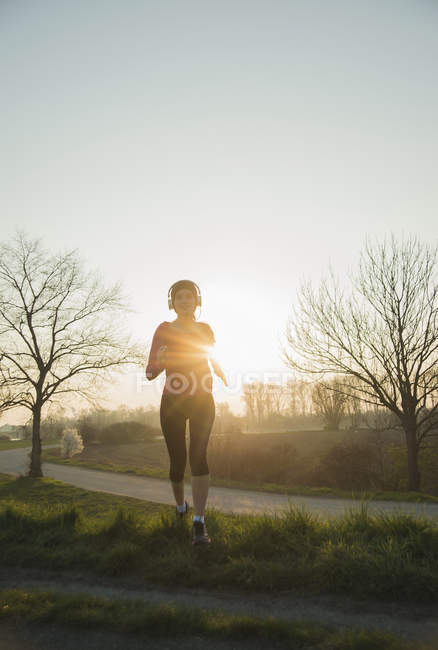 Молода жінка бігун, працює на заході сонця — стокове фото
