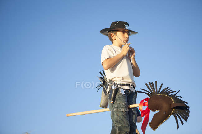 Boy dressed as cowboy fastening hat — Stock Photo