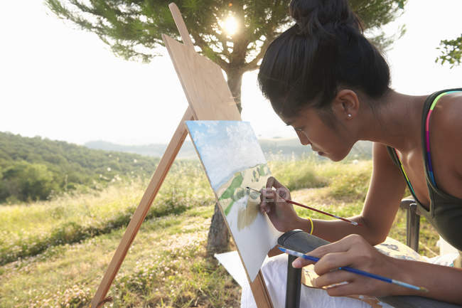 Young female artist painting landscape, Buonconvento, Tuscany, Italy — Stock Photo
