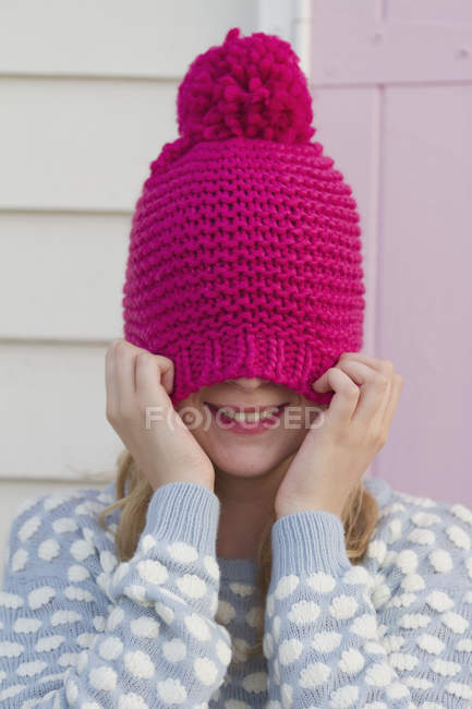 Portrait of young woman hiding under woolly hat — Stock Photo