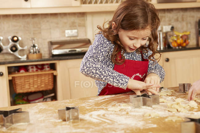 Menina assar forma de estrela pastelaria na mesa da cozinha — Fotografia de Stock