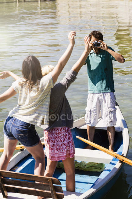 Hombre joven en barco en el lago fotografiando mujeres - foto de stock
