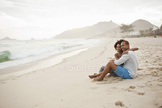 Пара сидящая на пляже, Рио-де-Жанейро, Бразилия — стоковое фото