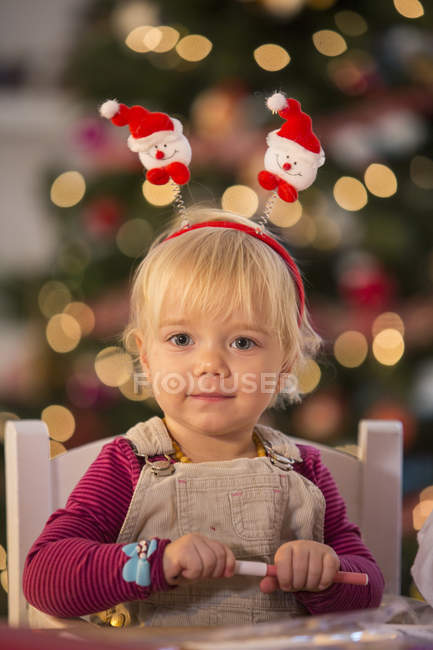 Girl in festive headband in room with Christmas tree — Stock Photo