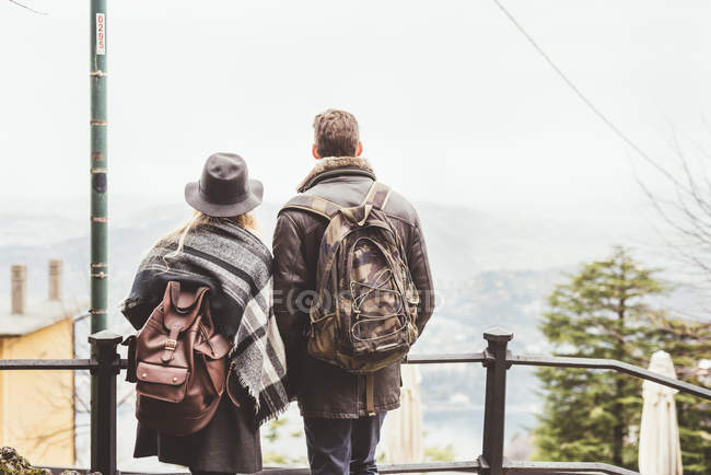 Rear view of young couple looking out at misty Lake Como, Italy — Stock Photo