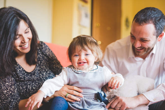 Mittleres erwachsenes Paar spielt mit Kleinkind-Tochter auf Sofa — Stockfoto