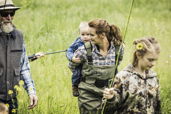 Família carregando varas de pesca no campo — Fotografia de Stock