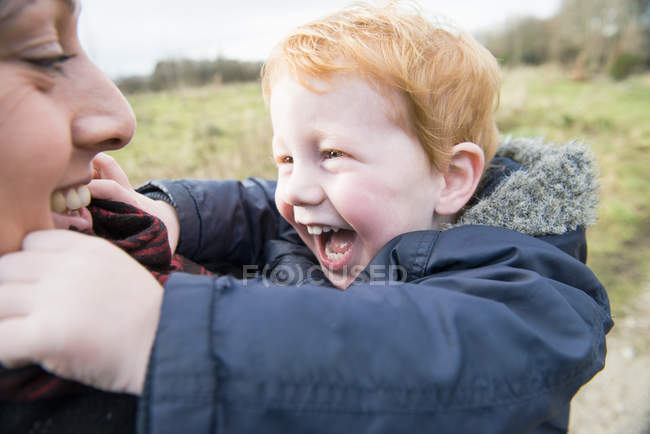 Maschio rossa bambino abbraccio madre all'aperto — Foto stock