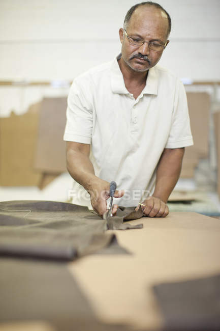 Upholsterer cutting leather with scissors — Stock Photo