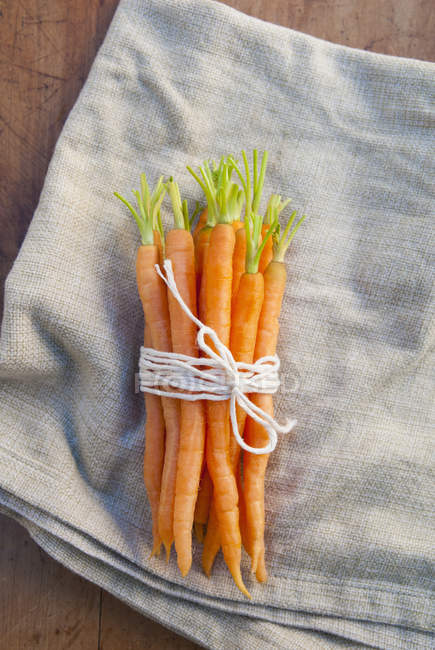 Mazzo di carote appena raccolte legate con spago su tovagliolo di stoffa — Foto stock