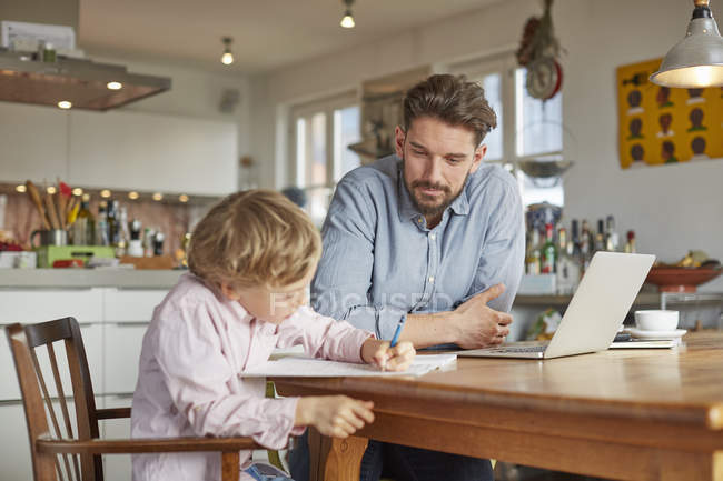 Vater hilft Sohn bei Hausaufgaben im Homeoffice — Stockfoto
