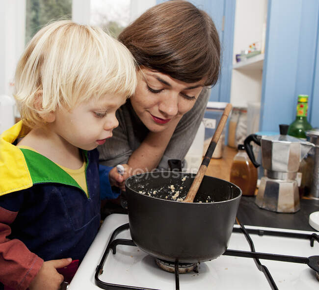 Mother and son waiting for porridge to cook in kitchen — Stock Photo