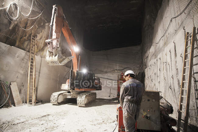 Worker and excavator in a marble quarry — Stock Photo