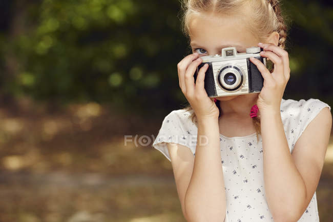 Menina usando câmera de filme, olhando para a câmera, rosto obscurecido — Fotografia de Stock