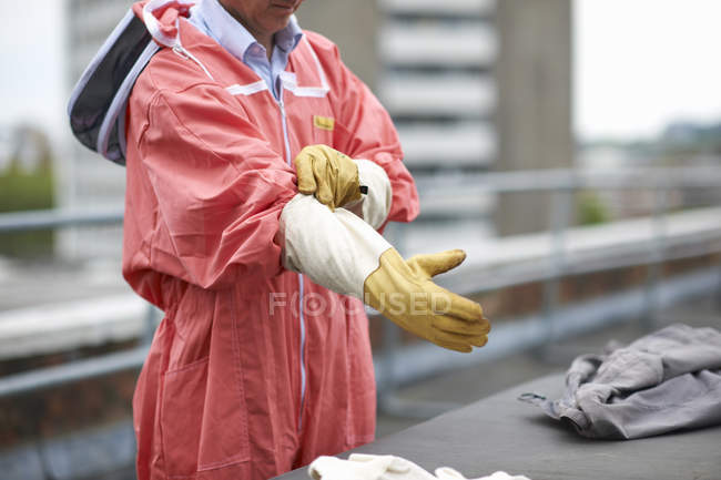 Cropped image of Beekeeper putting on beesuit — Stock Photo