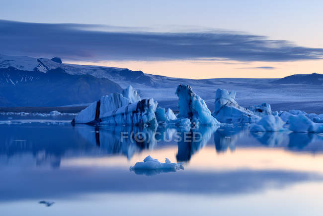 Eisberge, die sich im Wasser spiegeln und wolkenverhangener Himmel im Hintergrund, jokulsarlon Lagune, Island — Stockfoto