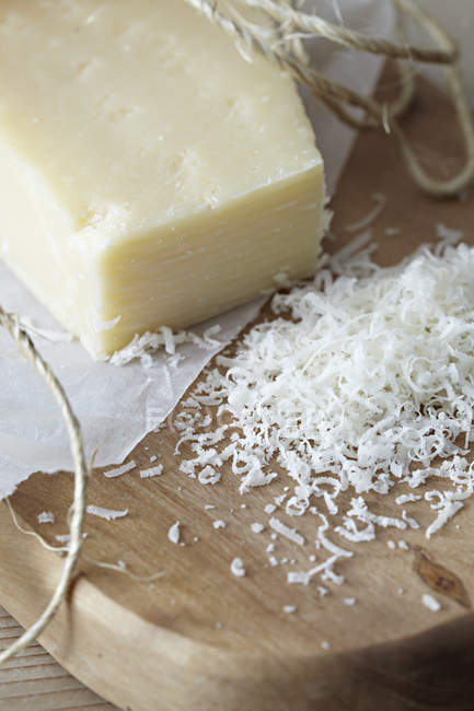 Grated parmesan on chopping board — Stock Photo