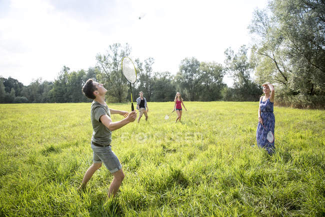 Група молодих людей, які грають у бадмінтон у полі — стокове фото